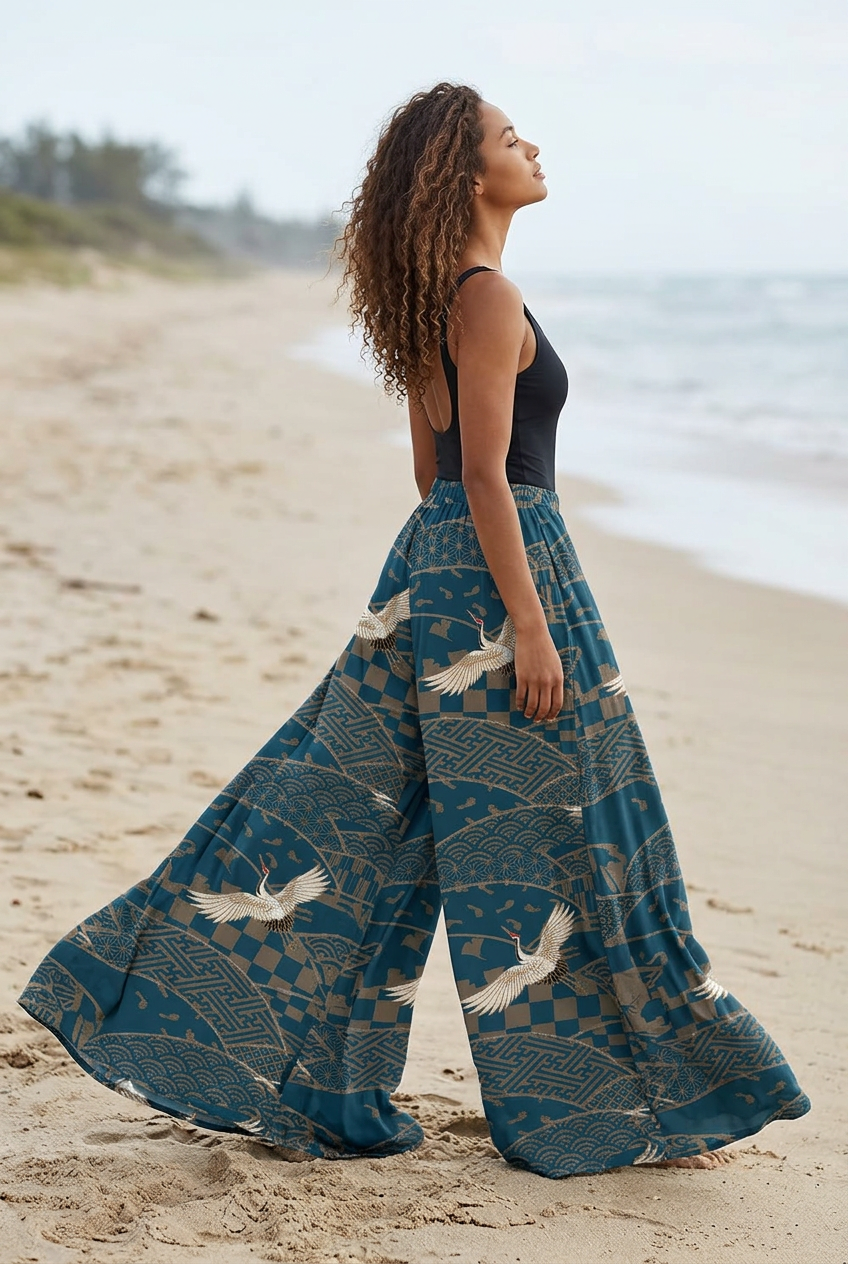 Pantalon palazzo bleu à grues, très long et ample, traînant sur le sable et ondulant au vent